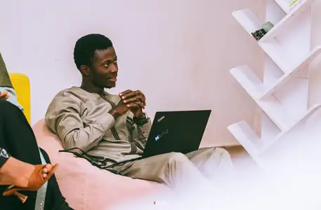 Un étudiant sourit en travaillant sur son ordinateur portable